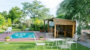 Un jardin avec une piscine, un espace salon extérieur et une pergola.