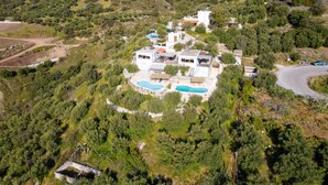 A hillside property with a swimming pool, multiple buildings, and a road. - Sarakinas Residences (Ierapetra)
