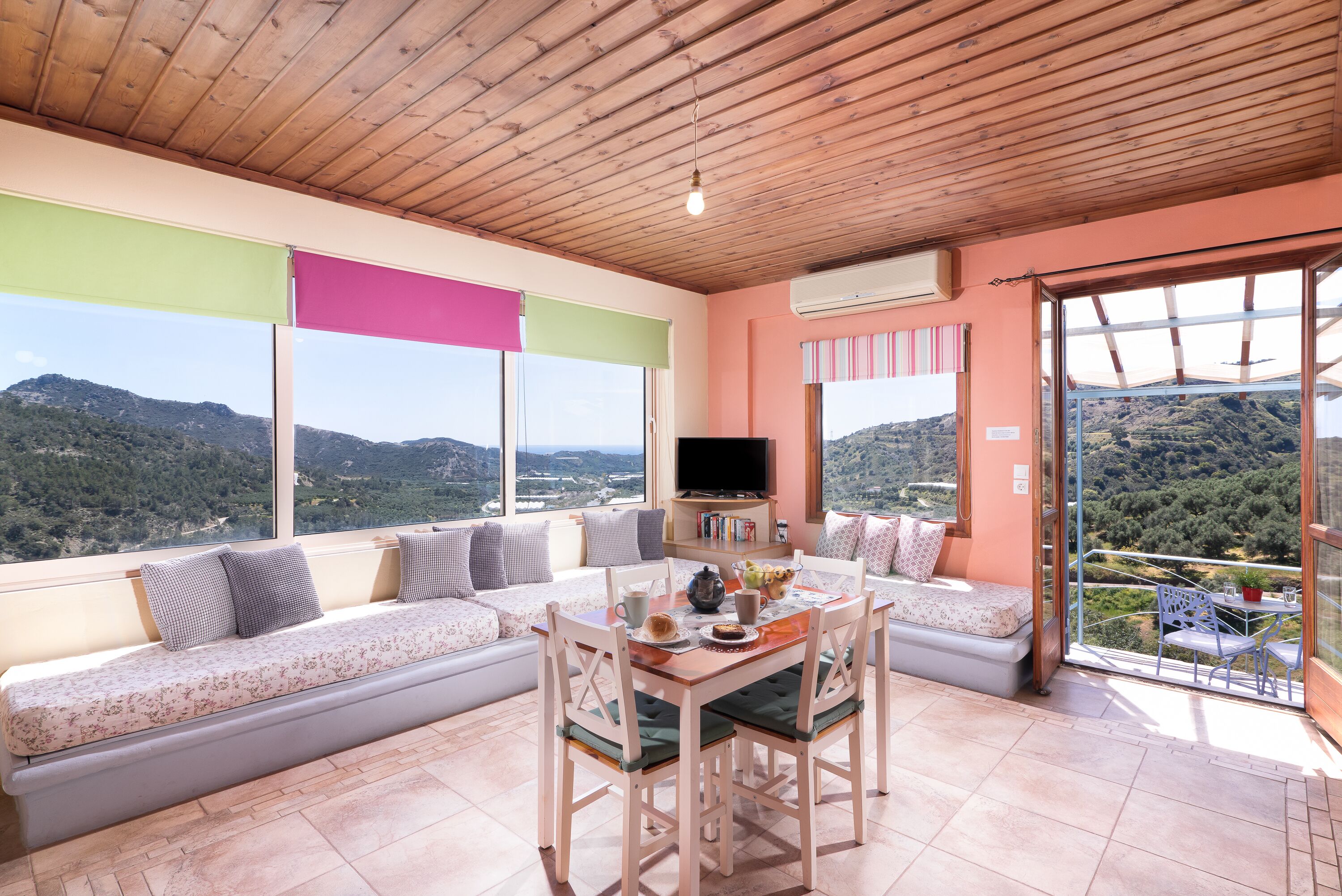 Una habitación acogedora con techo de madera, un sofá, una mesa de comedor y un televisor.