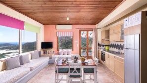 A cozy kitchen with a dining area, wooden ceiling, and a large window overlooking a scenic view. - Sarakinas Residences (Ierapetra)