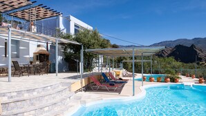 A swimming pool with lounge chairs, a pergola, and a view of mountains. - Sarakinas Residences (Ierapetra)