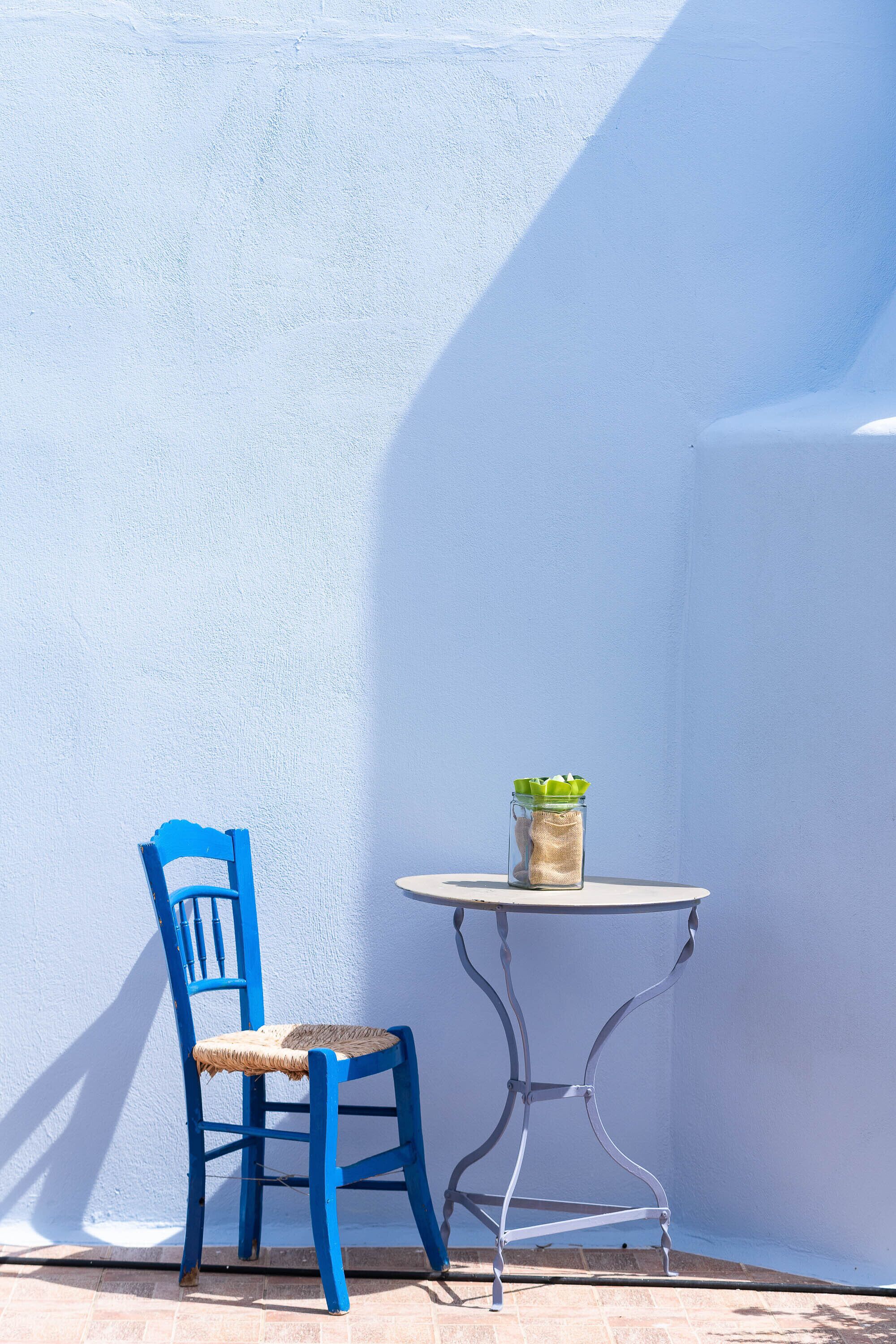 A blue chair and a small round table with a jar of sugar and a green plant.