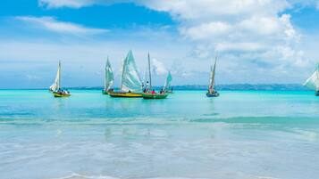 Na praia, areia branca, espreguiçadeiras, guarda-sóis