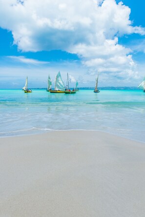 Na praia, areia branca, espreguiçadeiras, guarda-sóis 
