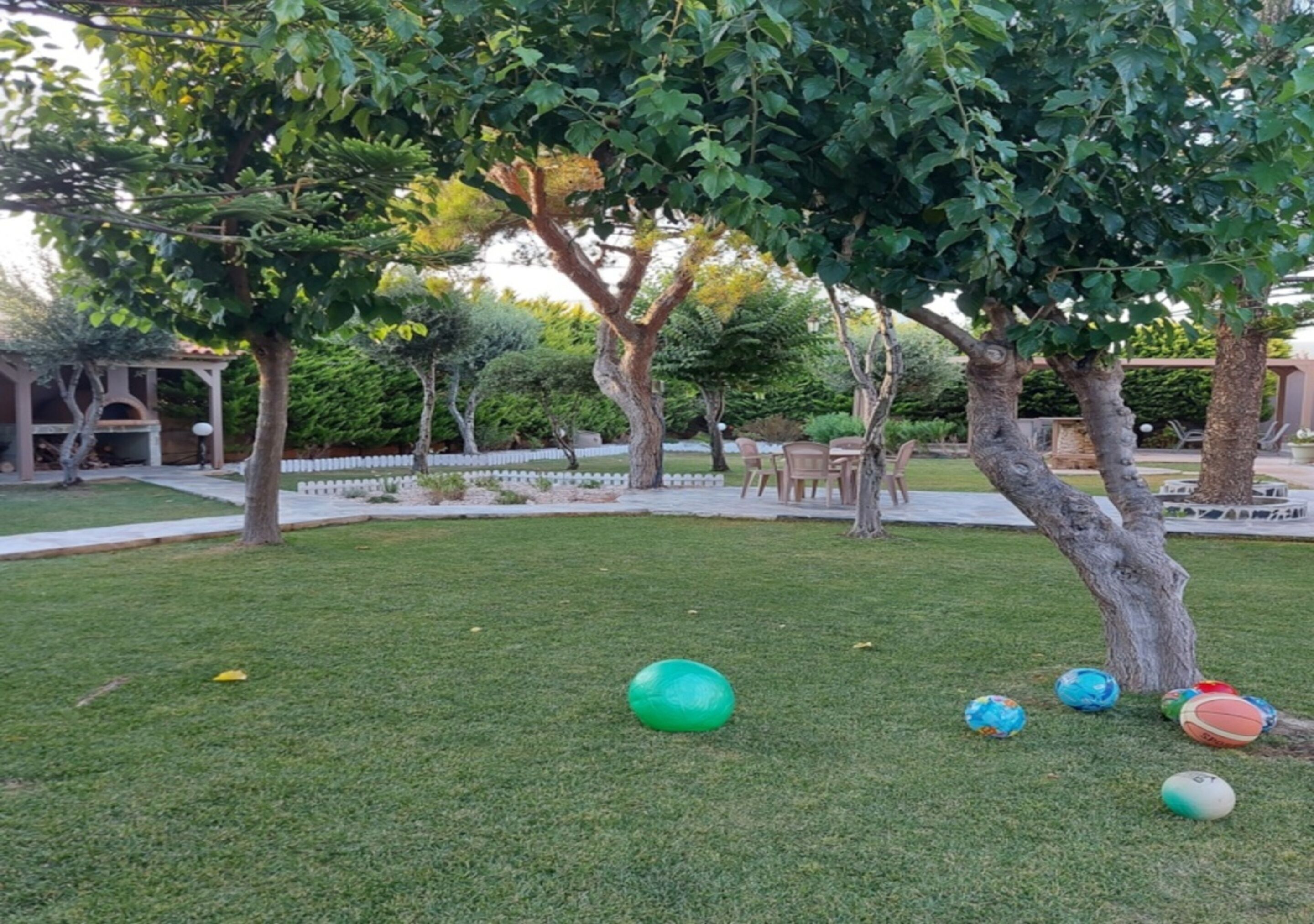 Un espacio al aire libre con césped, árboles y una cerca blanca.