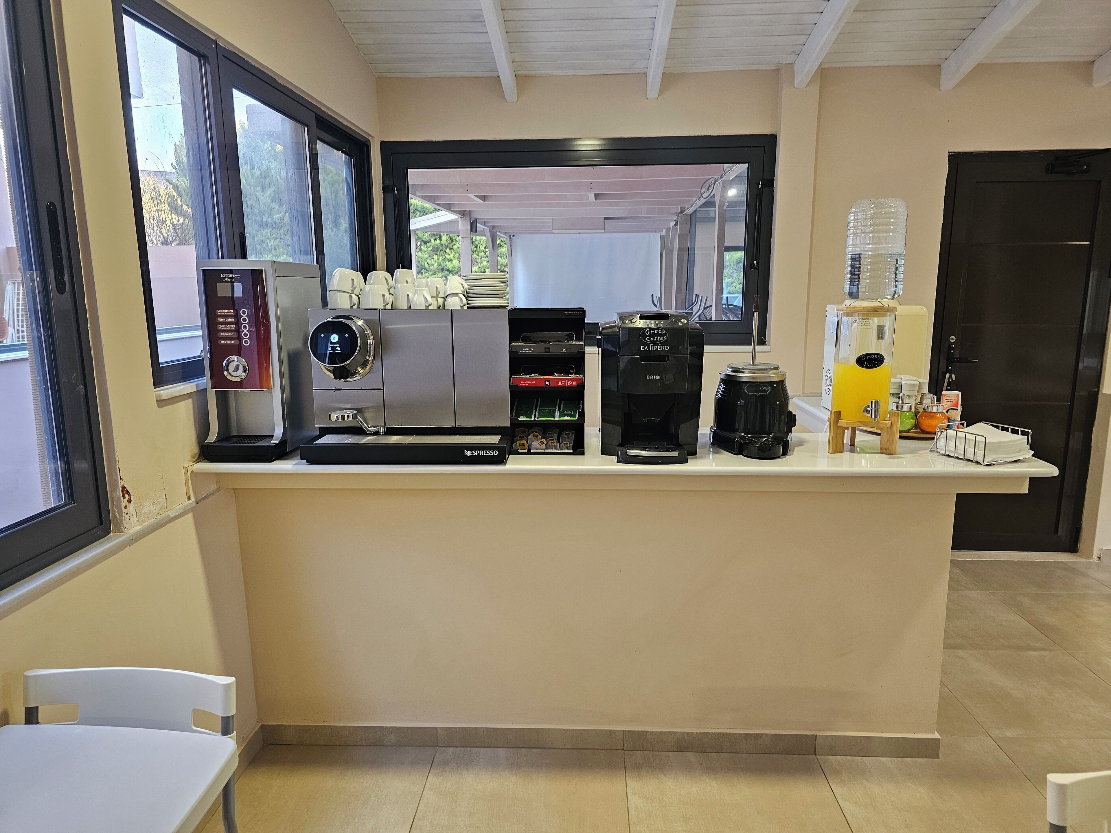 A coffee station with a Nespresso machine, a Greek coffee maker, and a water dispenser.