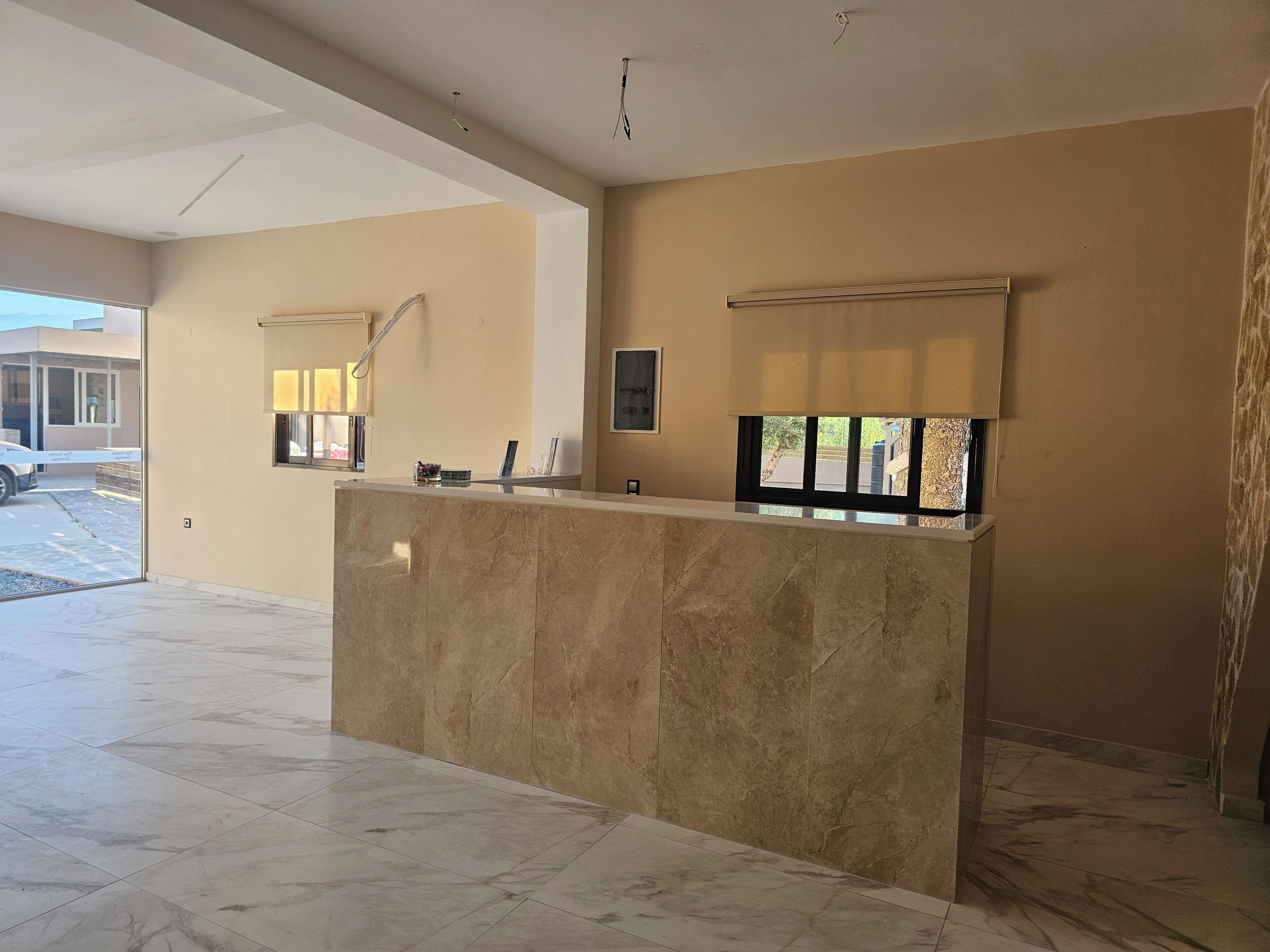 A reception area with a marble counter, a large window with blinds, and a view of the outside.