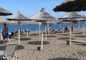 A beach with thatched umbrellas and lounge chairs. - The Santo George Beach Resort (Malevizi)