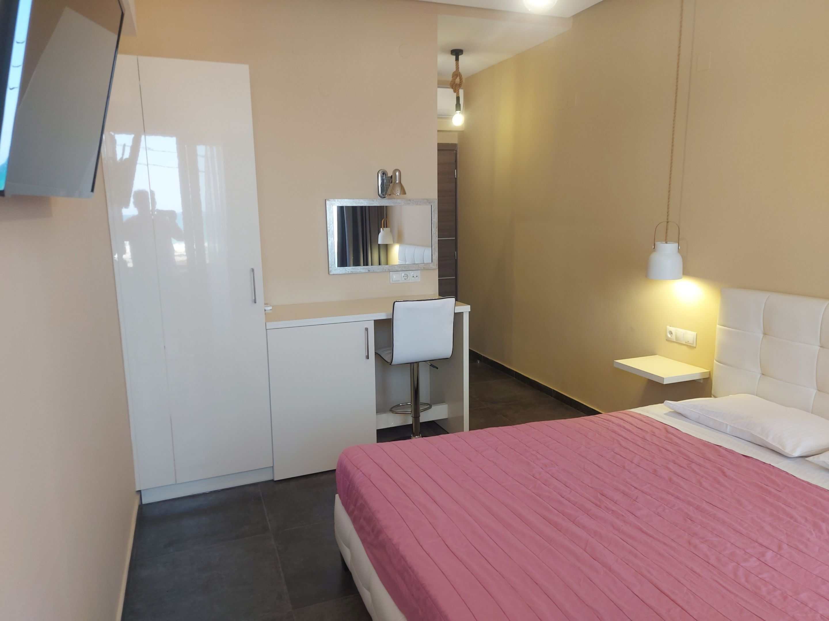 Une chambre à coucher comprenant un lit, un bureau, une chaise, une armoire et un miroir.