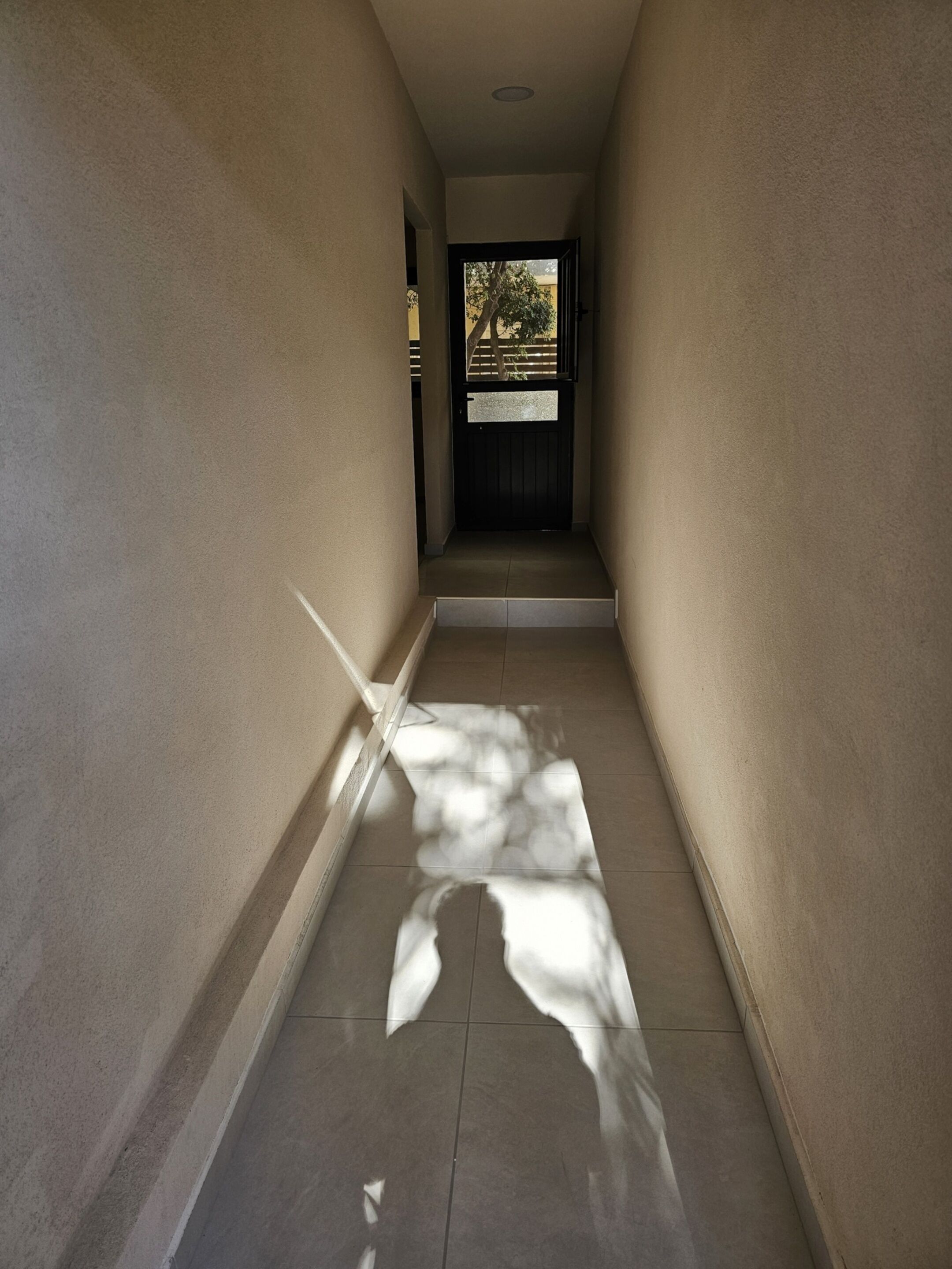 A narrow, tiled hallway with a door at the end.