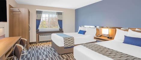 A hotel room with two beds, a desk, chairs, a TV, and a window with curtains.