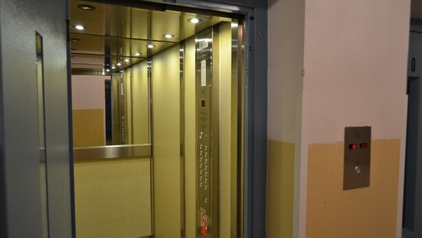 An elevator interior with metallic walls, a control panel, and a digital display. - Apartment Alejní (Teplice)