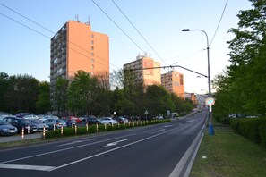 A multi-story building with balconies, a parking lot with cars, and a no parking sign on the side of the road. - Apartment Alejní (Teplice)