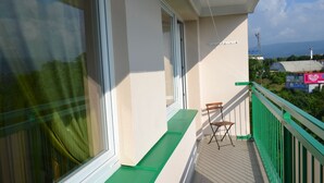 A balcony with a green railing, a window with a curtain, and a chair. - Apartment Alejní (Teplice)