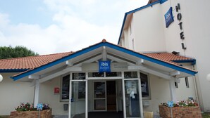 A hotel entrance with a blue roof, glass doors, and a sign indicating it's an ibis budget hotel. - ibis Budget Dax Saint Paul les Dax (Saint-Paul-les-Dax)