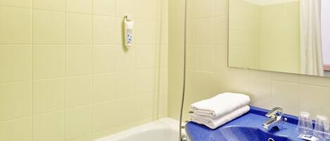 A bathroom with a white bathtub, a blue sink, and a mirror above the sink.