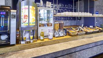 A self-service breakfast station with coffee machines, juice dispensers, and a variety of breakfast items.