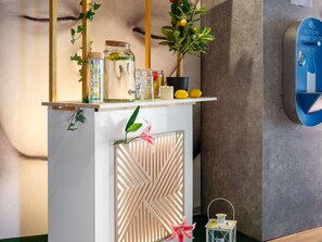 Zona de bar moderna con mostrador de madera, dispensador de agua y diferentes botellas y vasos.
