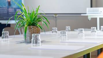 Une table de conférence ornée d’une plante en pot et de bouteilles en verre transparent.
