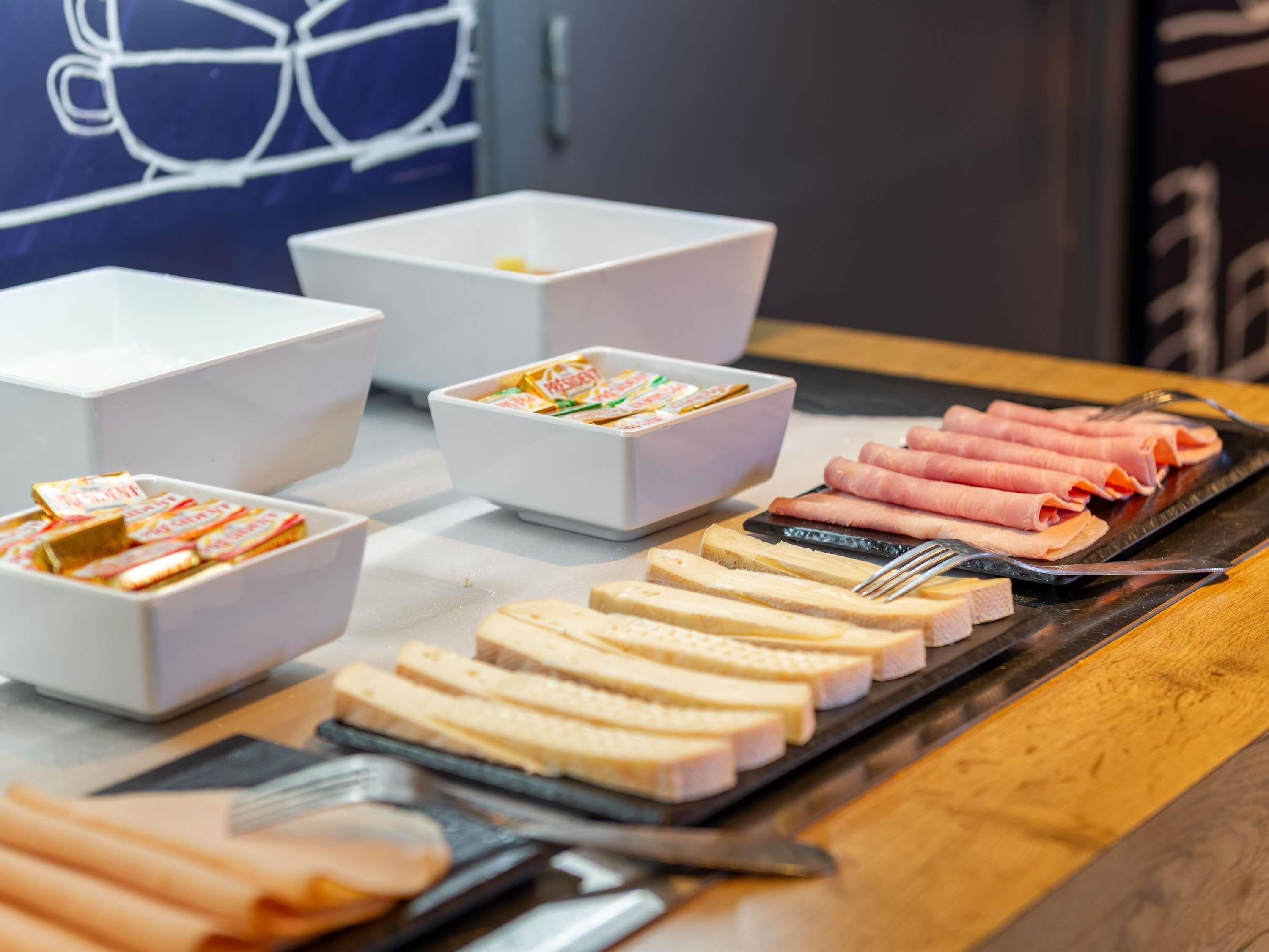 A buffet with various food items including sliced meats, cheeses, and packaged snacks.