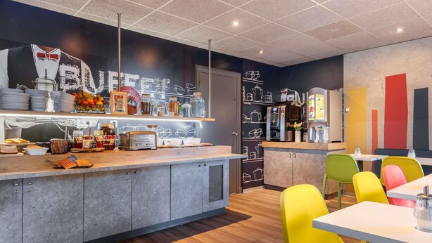 Ein modernes Café mit einer Theke, bunten Stühlen und einer Küchenzeile.