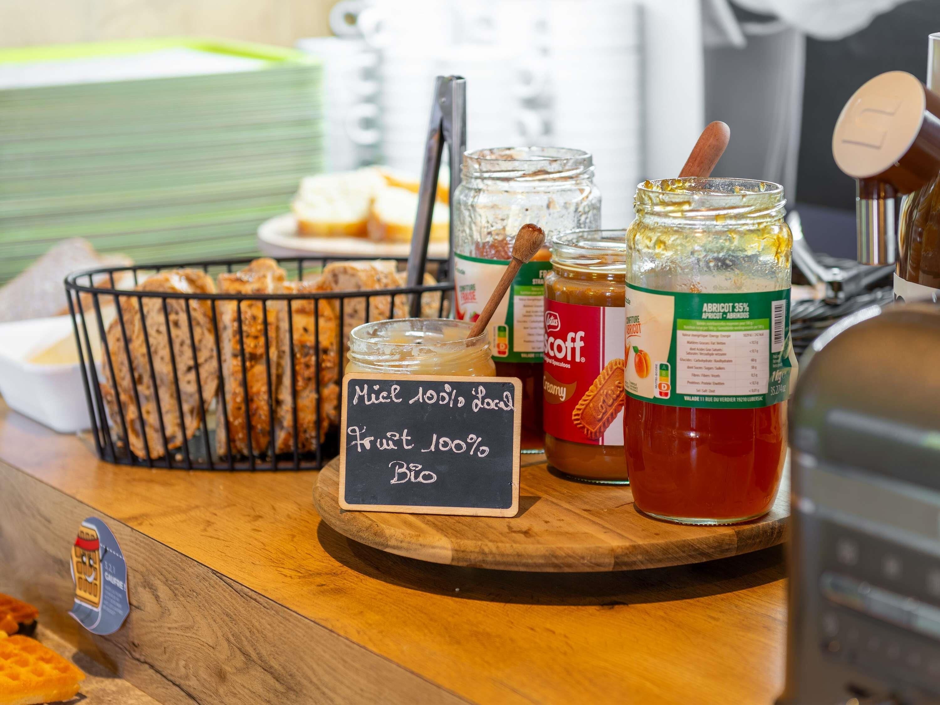 A bakery display with various baked goods and jars of jam.