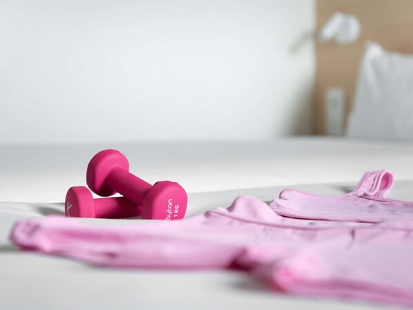 A bed with pink bedding and a pair of pink dumbbells on it. - ibis Budget Caen Mondeville (Mondeville)