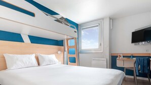 Ein Hotelzimmer mit einem großen Bett, einem Schreibtisch, einem Stuhl, einem Fernseher und einem Fenster.