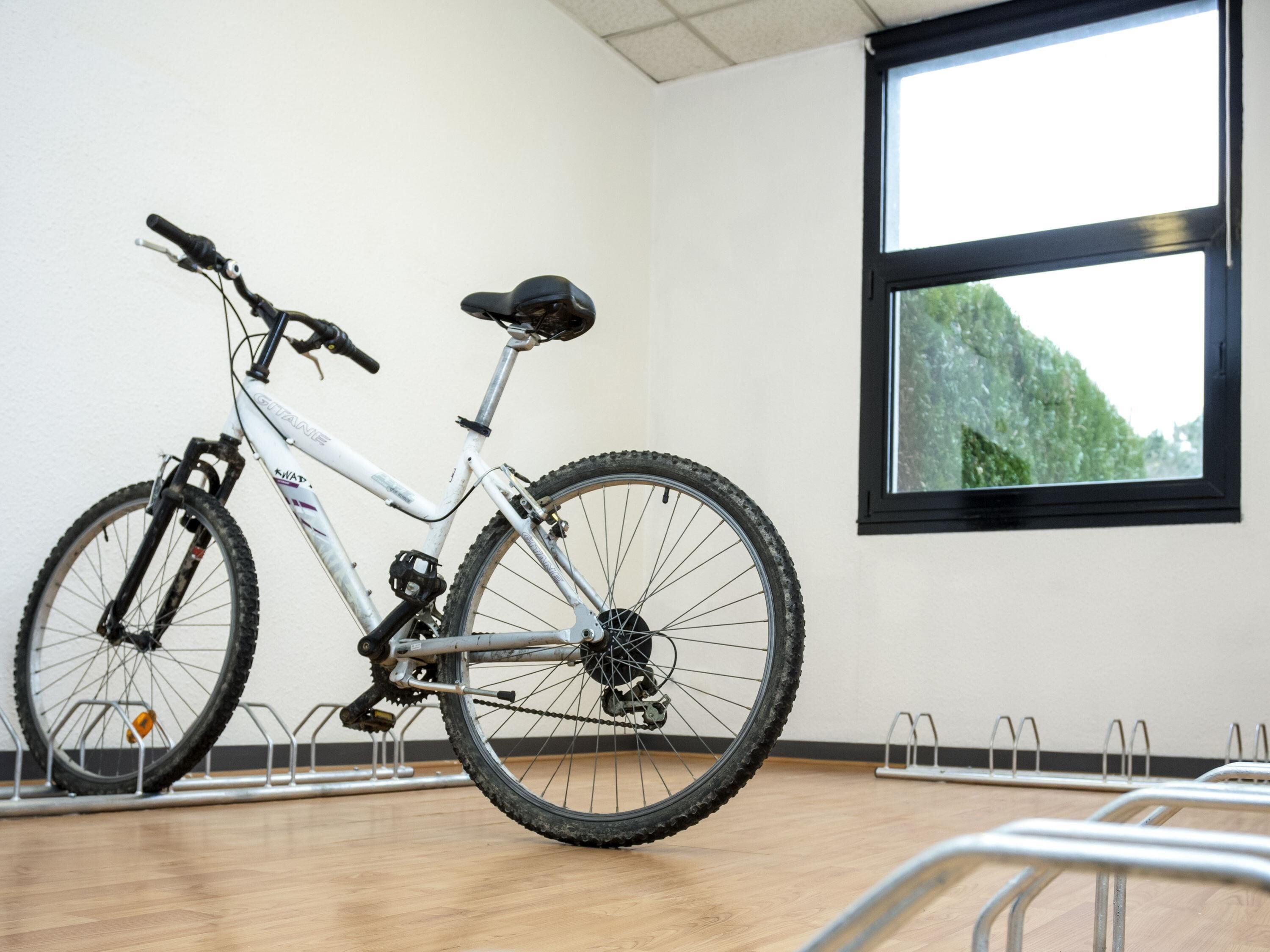 Un vélo blanc dans une pièce dotée d’une grande fenêtre et d’un plancher en bois.