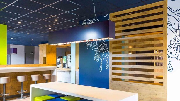 Un área de bar moderna con barra, taburetes y una pared con un diseño decorativo.