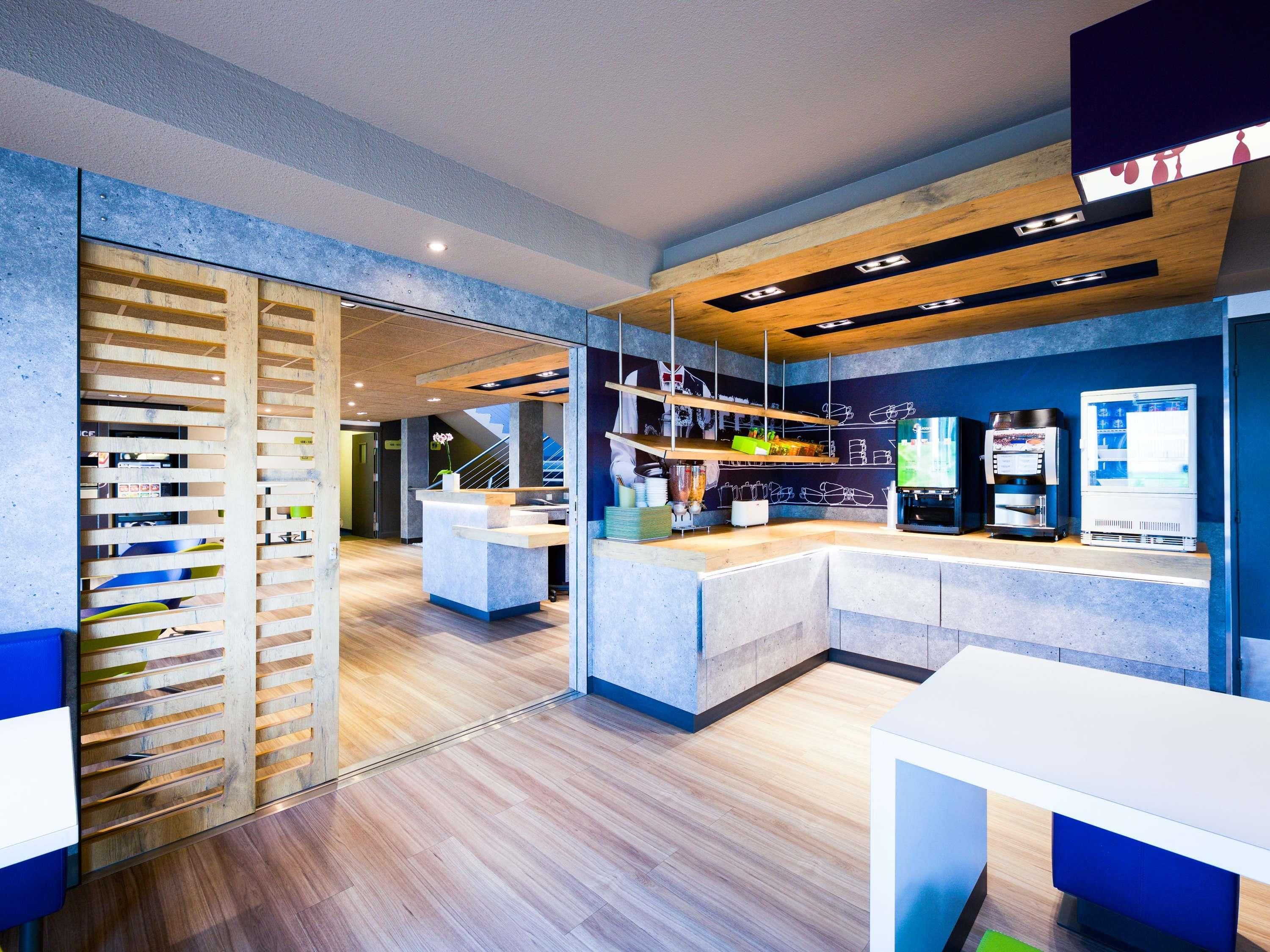 A modern reception area with a wooden slat partition, a reception desk, and a coffee machine.