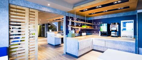 A modern reception area with a wooden slat partition, a reception desk, and a coffee machine.