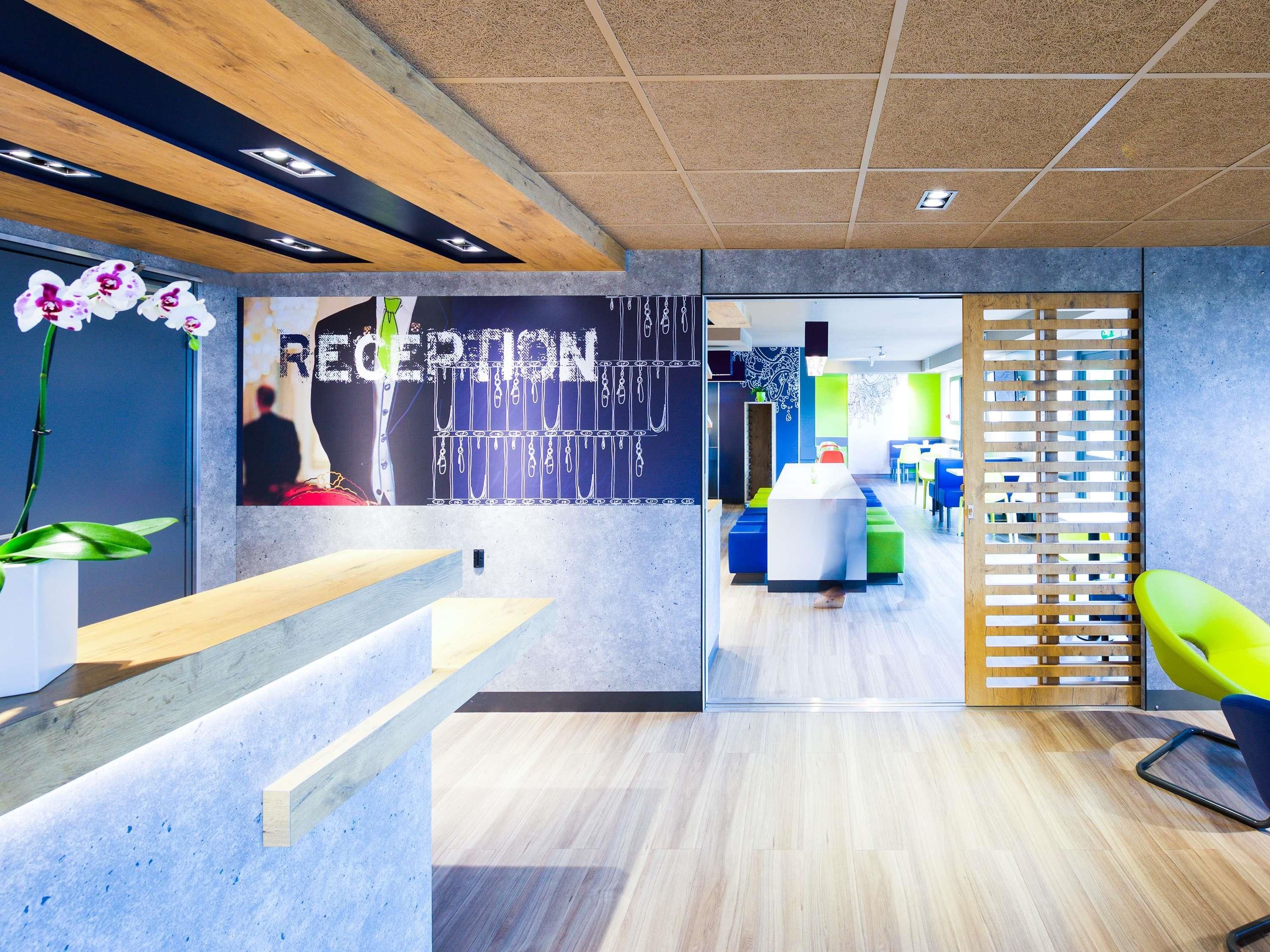 Un espace d’accueil au design moderne, comprenant un comptoir d’accueil, un espace salon et un mur portant l’inscription « RÉCEPTION ».