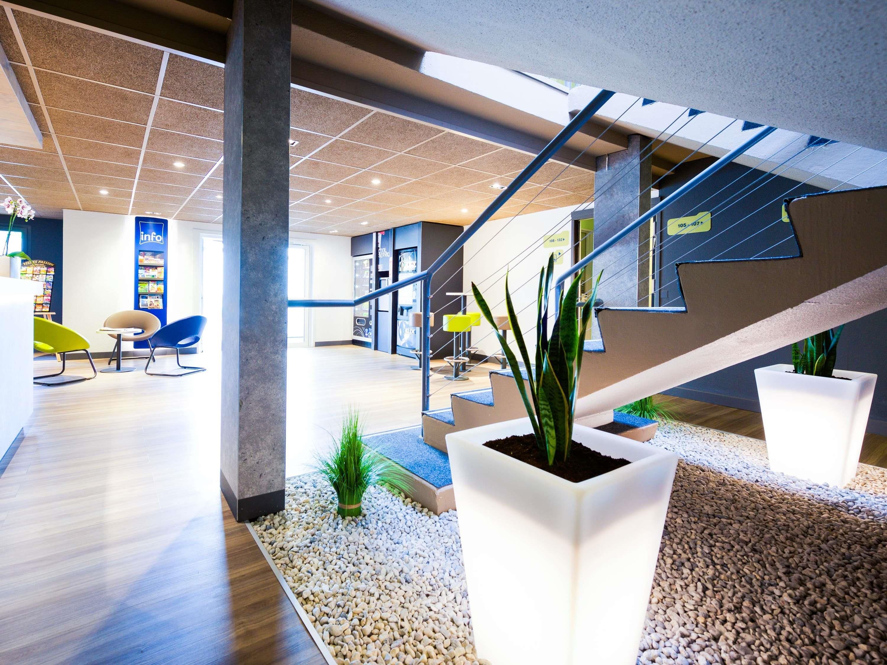 A modern indoor space with a staircase, seating area, and potted plants.
