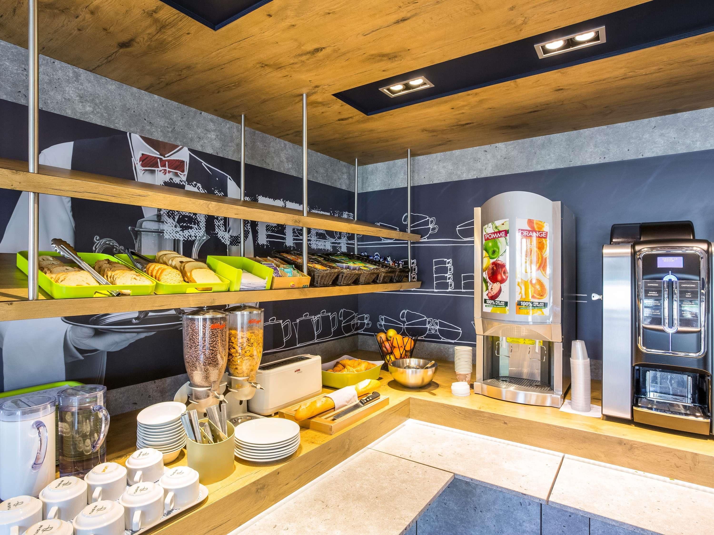 A breakfast buffet with various food items, a coffee machine, and a fruit dispenser.