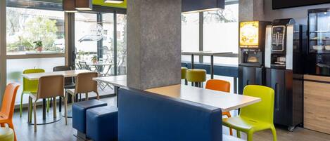 Un café moderno con mesas, una máquina de café y un amplio ventanal.