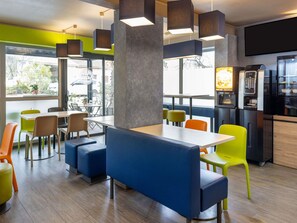 Een modern café met zitplaatsen, een koffieapparaat en een groot raam.