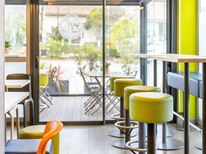 Een café interieur met tafels, stoelen en uitzicht op buiten.