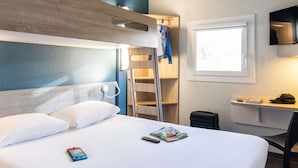 Une chambre d’hôtel avec un lit, un bureau, une chaise, une télévision et une fenêtre.