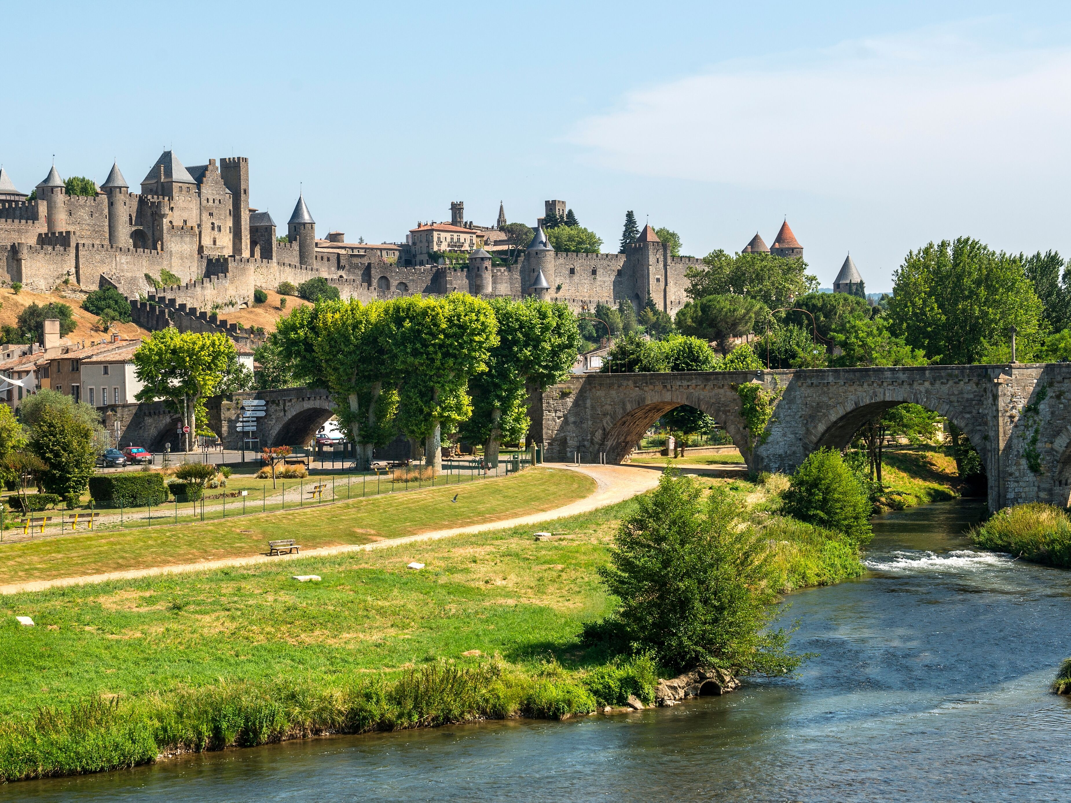A stone bridge over a river with a castle in the background.