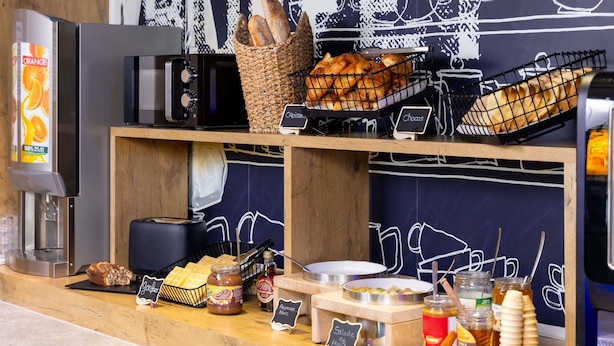 Un buffet pour le petit-déjeuner avec des croissants, du pain, des gaufres, des confitures et du miel.