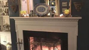 Una chimenea con fuego, rodeada de estantes con diversos objetos.