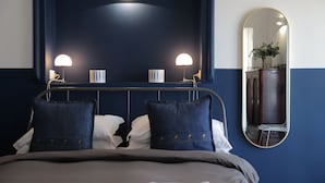 A neatly made bed with two pillows, a bedside lamp, and a mirror on the wall. - Salotto Borbonico (Naples)