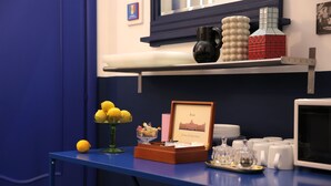 A blue table with a framed picture, a vase with lemons, a bowl of fruit, and a tray with glasses and plates. - Salotto Borbonico (Naples)