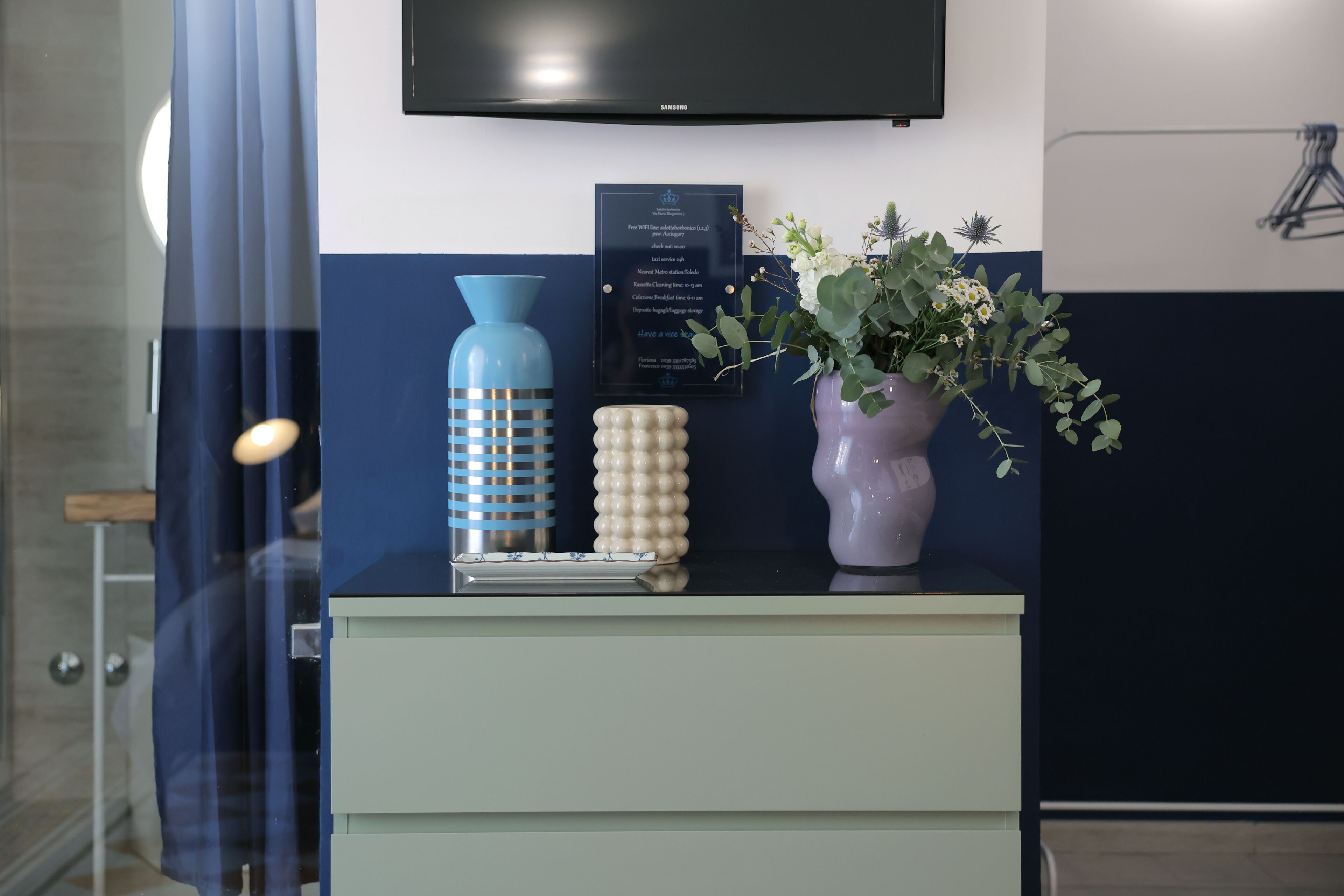 A modern bathroom with a shower, a sink with decorative items, and a mounted television.