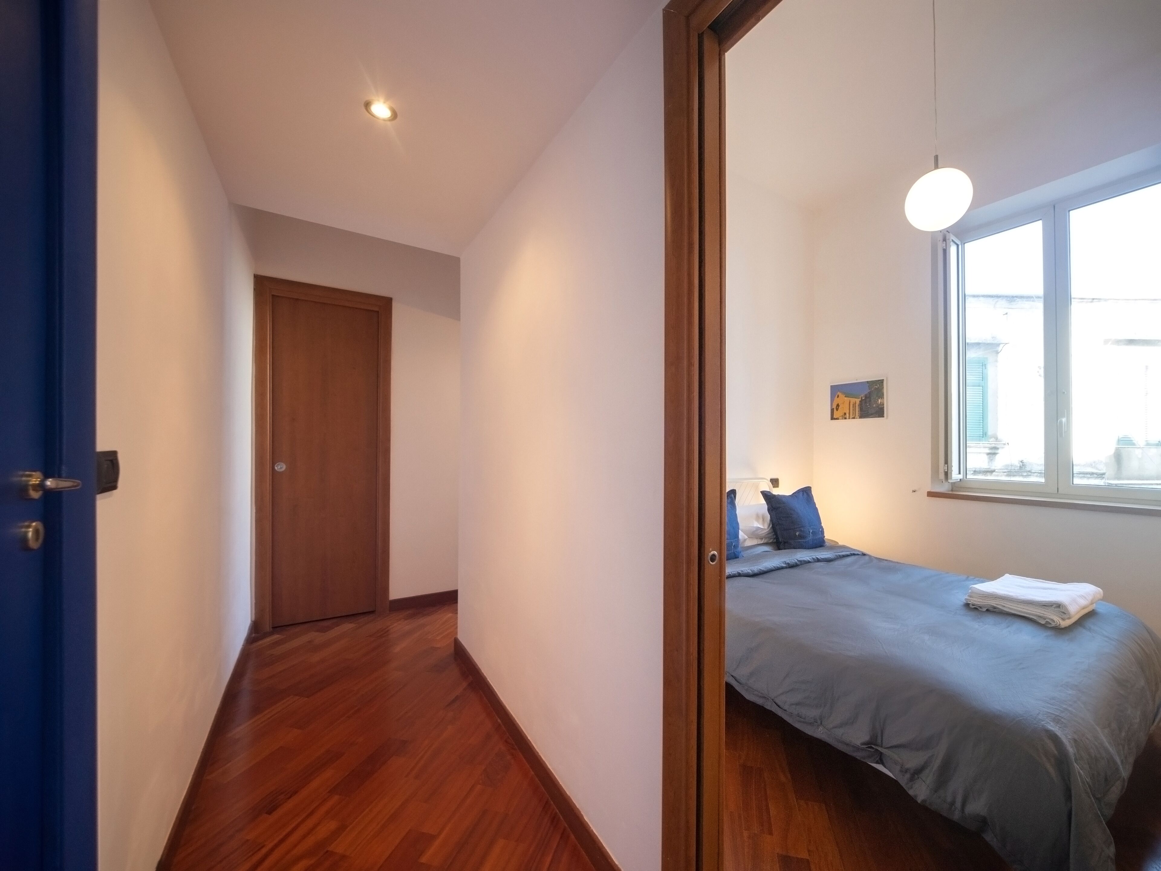 A bedroom with a bed, a window, and a door.