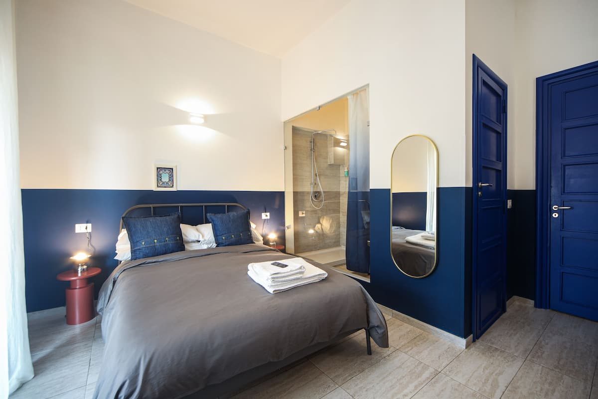 A bedroom with a bed, bedside table, and a mirror.