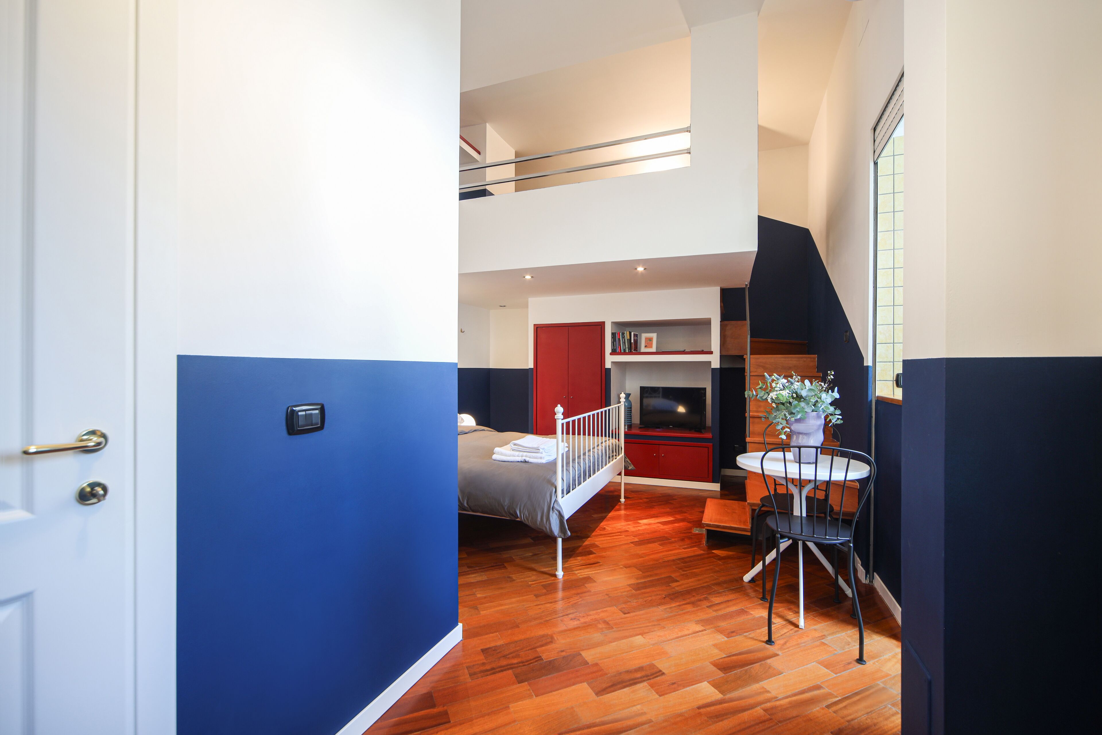 A modern hotel room with a bed, a small dining table, and a TV.