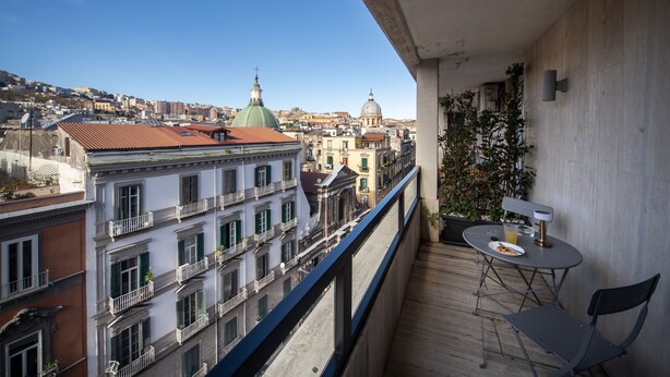 A balcony with a view of a cityscape, including buildings with domed roofs and a clear blue sky. - Salotto Borbonico (Naples)