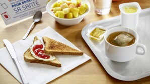 A breakfast tray with toast, jam, tea, and a bowl of fruit. - ibis Budget Lyon Eurexpo Chassieu (Chassieu)